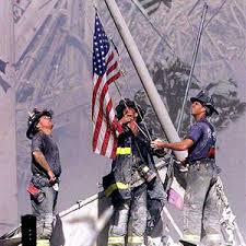 Firefighters raise U.S. flag amidst the debris of the Twin Towers.