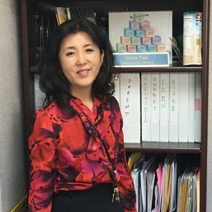 Ms. Elena Paul standing before a bookshelf