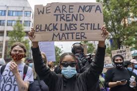 A Black Lives Matter protester holding a sign talking about the trend of the BLM movement 